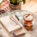 A journal, pen, and cup of tea arranged on a rustic table for a peaceful journaling session.